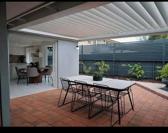 Custom dark slat privacy screen behind a finished Adelaide patio and outdoor dining area